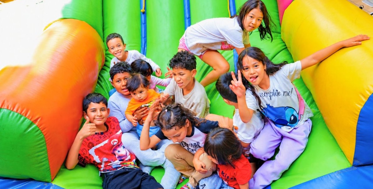 Un grupo de niñas y niños juega y posa sonriente en un inflable durante una fiesta infantil