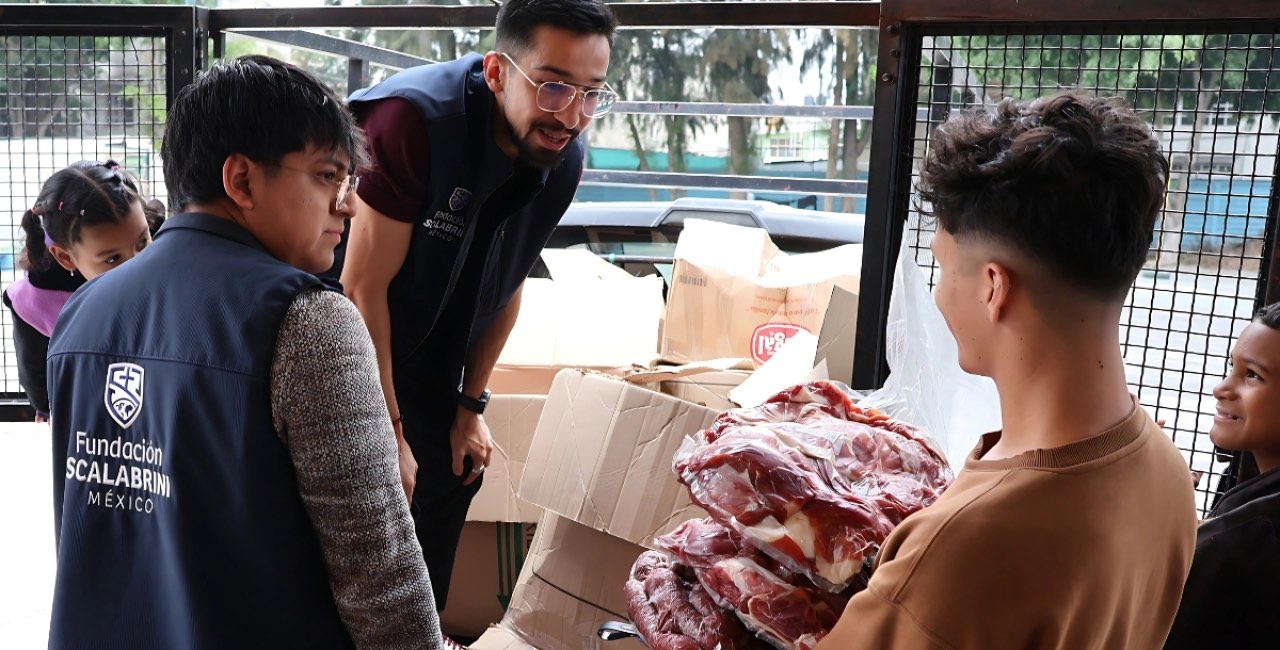 Personal de la Fundación Scalabrini descarga cajas y despensa donada en la entrada de una de las casas