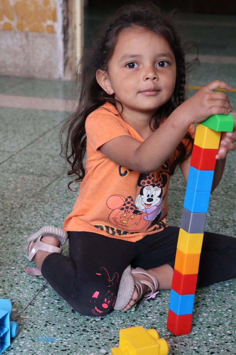 Niña juega con bloques de colores en el área infantil de una casa de acogida